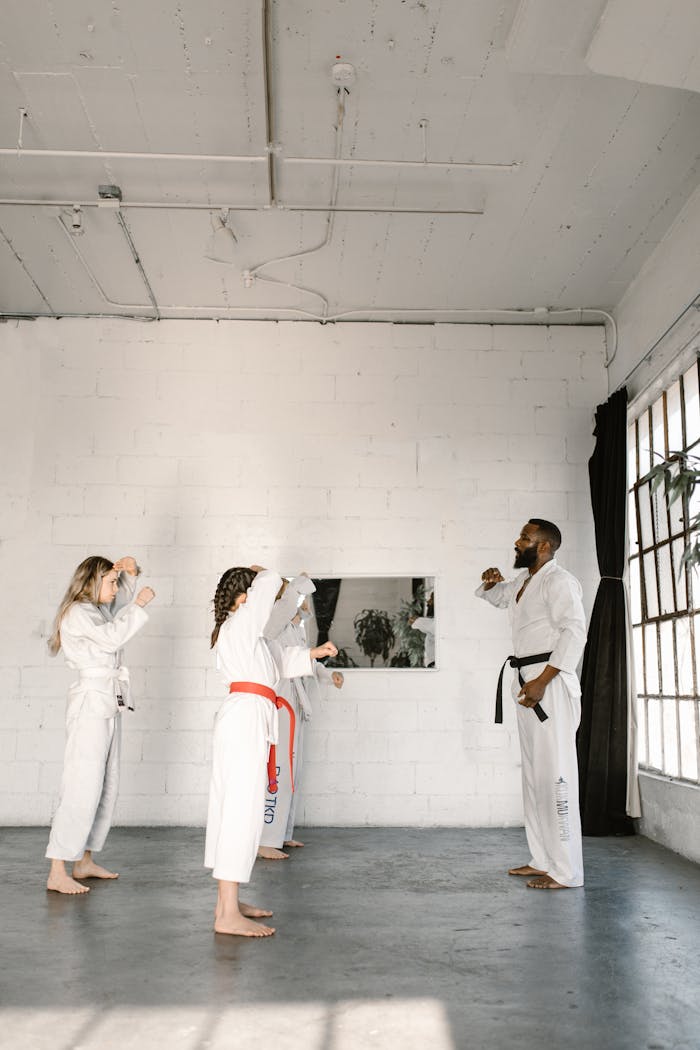 Martial arts instructor teaching young students karate techniques in a bright studio.